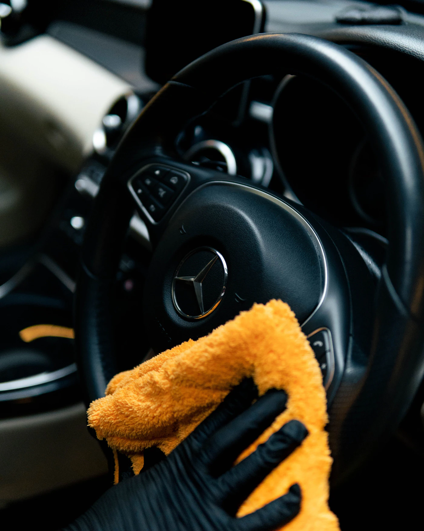 Detailer in a glove wiping a car interior with a microfiber towel during a professional pet hair removal and interior detailing service in NH